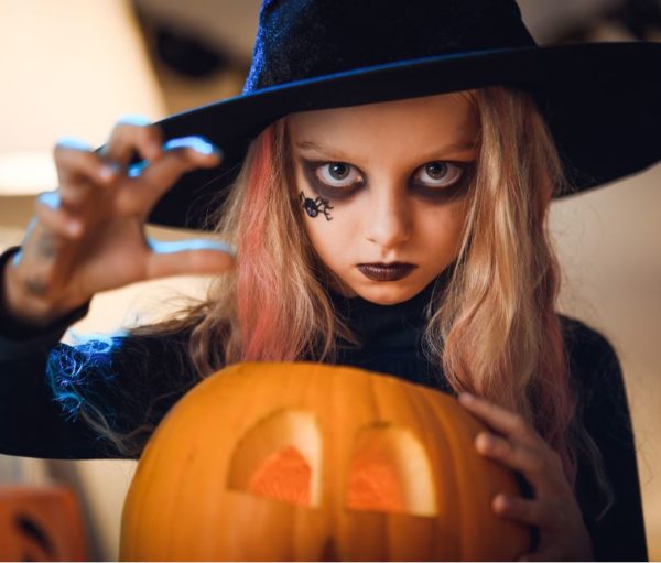 girl dressed as witch with a jack-o-lantern